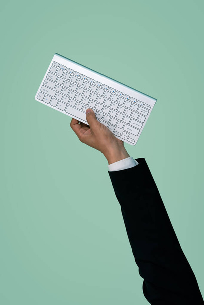 Hand hält drahtlose Tastatur auf isoliertem Hintergrund für Start-up-Tech-Unternehmen. Umweltfreundliche grüne Unternehmen fördern die Idee der Elektroschrottpolitik. Urig - Foto, Bild