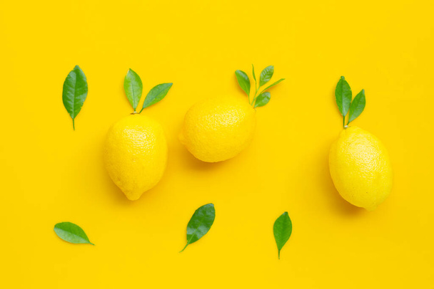 Friss citrom zöld levelekkel sárga alapon. - Fotó, kép
