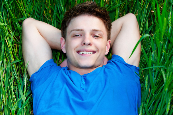 Young man lying on green field - Photo, Image