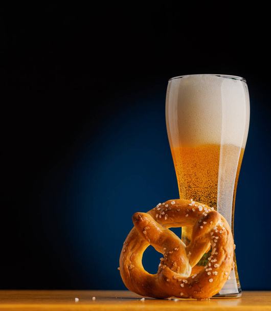 Cerveza en la barra: Refrescante cerveza de barril y pretzel en una mesa de madera. Con espacio de copia - Foto, Imagen