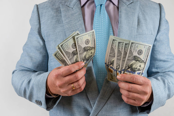 Uomo in possesso di banconote in denaro isolato sfondo grigio. Concetto di investimento finanziario - Foto, immagini