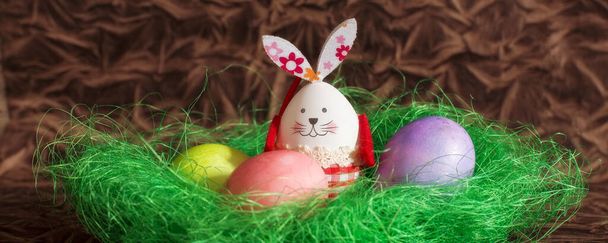 Barevné velikonoční vejce a zajíček králík v zelené další dekorace na hnědé kopie prostor na pozadí banner - Fotografie, Obrázek