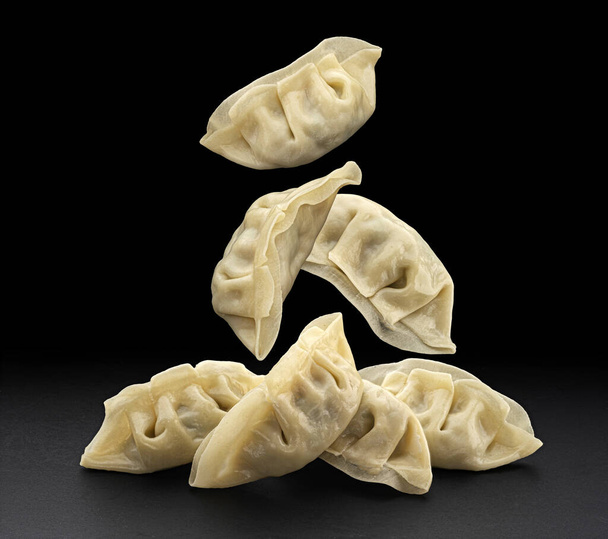 Falling Chinese Gyoza dumplings isolated on black background with copy space - Photo, Image