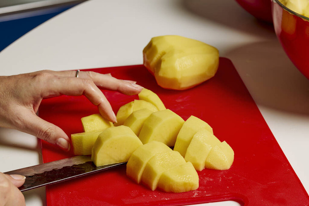 Mani di donna con un coltello taglio patate da cuocere. - Foto, immagini