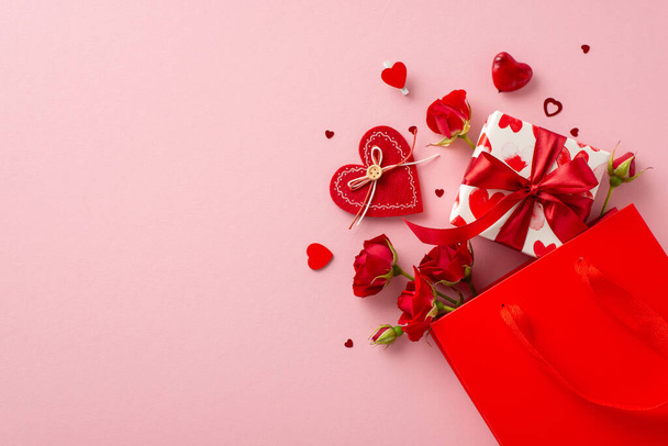 Romantyczna niespodzianka czeka! Widok z góry strzał papierowej torby z tematyczne pudełko na prezenty, ozdobione miłosnym wzorem papieru. Czerwone róże, konfetti w kształcie serca na pastelowym różowym tle, pozostawiając miejsce na słodką wiadomość - Zdjęcie, obraz