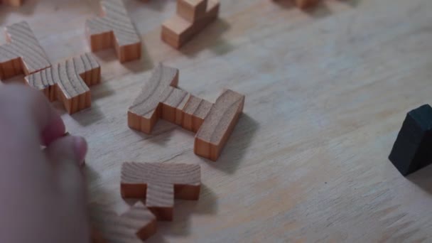 Close-up hand een kleine jongen spelen houten blokken speelgoed in de woonkamer thuis - Video
