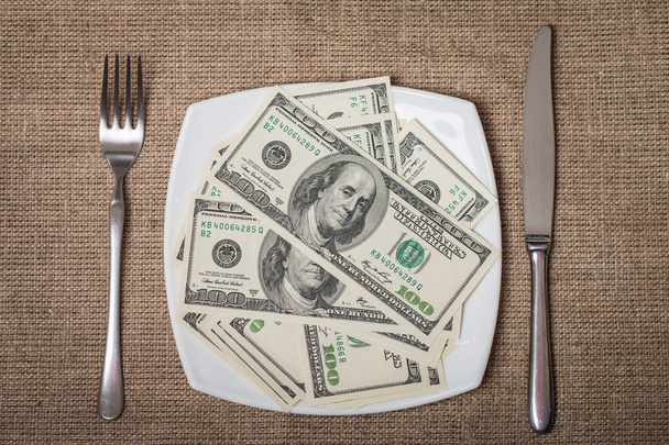 Χρήματα σε ένα λευκό πιάτο με μαχαίρι και πιρούνι - Φωτογραφία, εικόνα