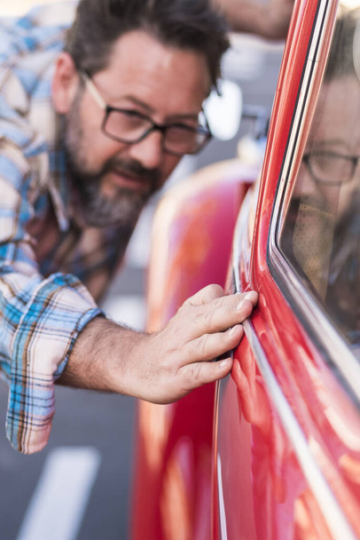 Homem barbudo adulto verificar o polonês de seu belo carro ao ar livre - pessoas e automóvel conceito de amor e cuidado de transporte - motorista olhar o exterior de seu automóvel - Foto, Imagem