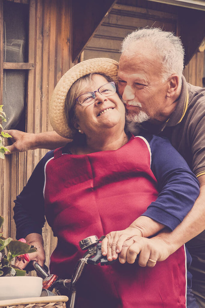 Happy senior couple enjoy have fun outdoor at home in the garden - cheerful mature man and woman together smile and laugh in joyful lifestyle - caucasian old people and happiness - Photo, Image
