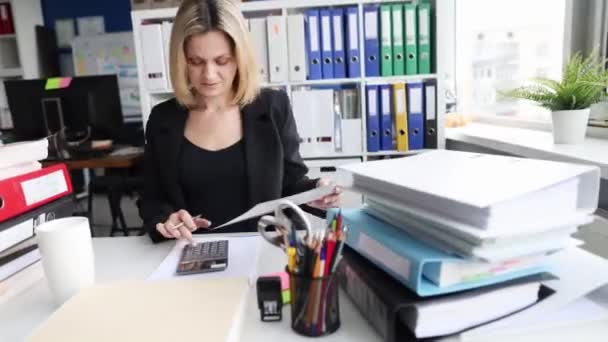 Young business woman sums up cost of project hyperlapse. Businesswoman using calculator and computer accounting data and planning budget or estimating financial audit taxes - Footage, Video