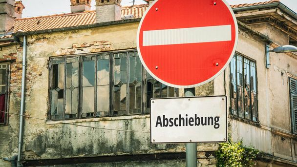 Un'immagine con un cartello che punta in due direzioni diverse in tedesco. Una direzione punta all'asilo, l'altra punta alla deportazione. - Foto, immagini
