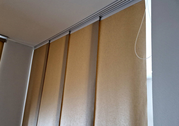  uitschuifbaar hanggordijn is een scheidingswand van beige jaloezieën van textiel. startscherm in de woonkamer of eetkamer. rails en reiskabel - Foto, afbeelding