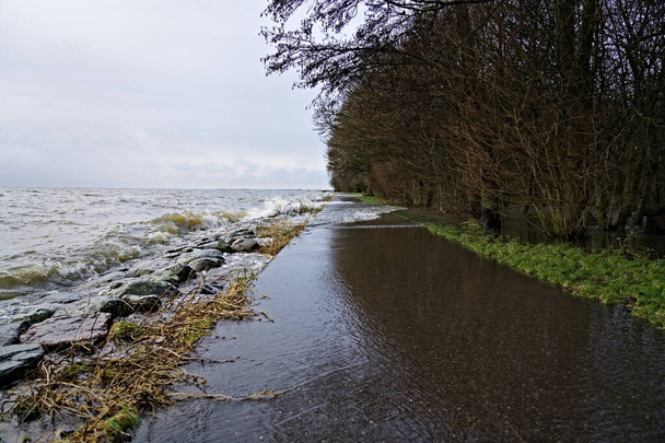 Alto nivel de agua debido a las fuertes lluvias y tormentas, las olas del lago Markermeer se estrellan sobre el dique de piedra y el sendero e inundan la ciudad del parque de Hoorn, Países Bajos - Foto, imagen