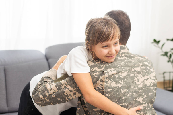 Uma menina bonita a abraçar o pai militar. Foto de alta qualidade - Foto, Imagem