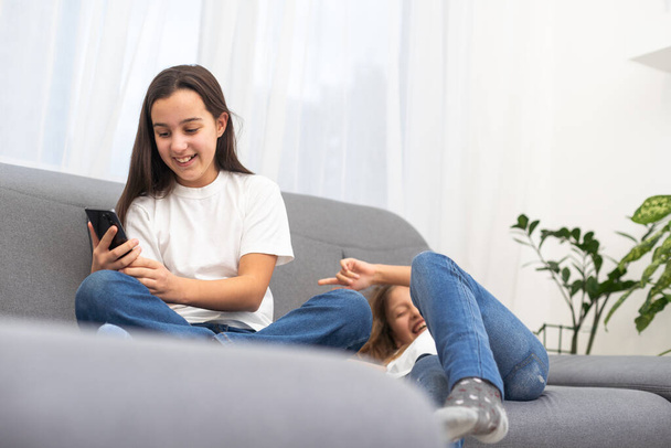 幸せな女子高生は彼女の友人の近くに横たわり,チャットのために新しいスマートフォンを使用しています. 高品質の写真 - 写真・画像