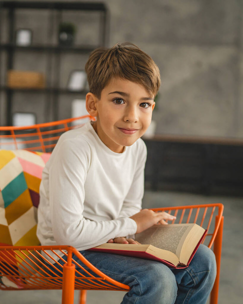 Un ragazzo caucasico bambino di sette anni bambino in camera a casa leggere libro - Foto, immagini