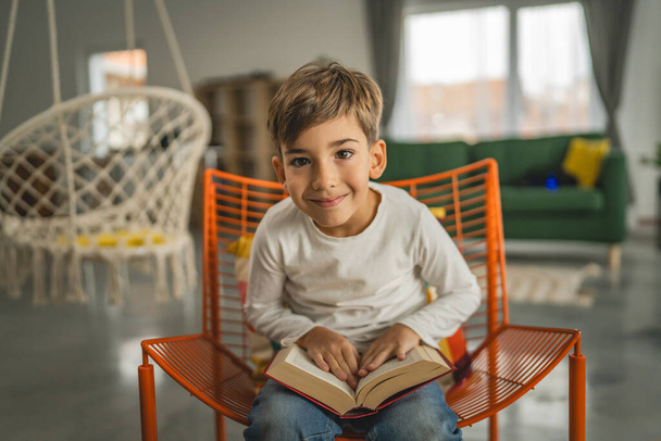 Een jongen Kaukasisch kind zeven jaar oud kind in kamer thuis lees boek - Foto, afbeelding