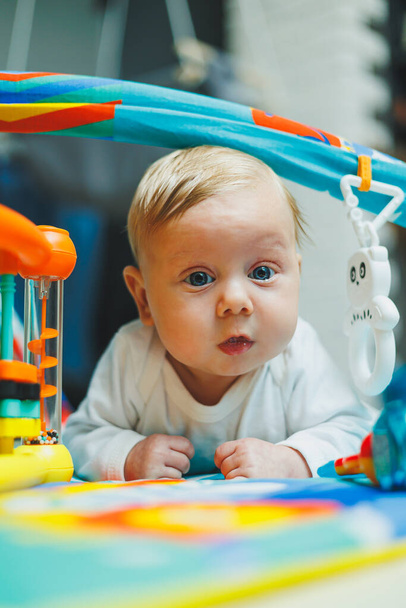 Ein Baby spielt zwei Monate lang auf einer Entwicklungsmatte. Spielteppich für kleine Kinder. - Foto, Bild