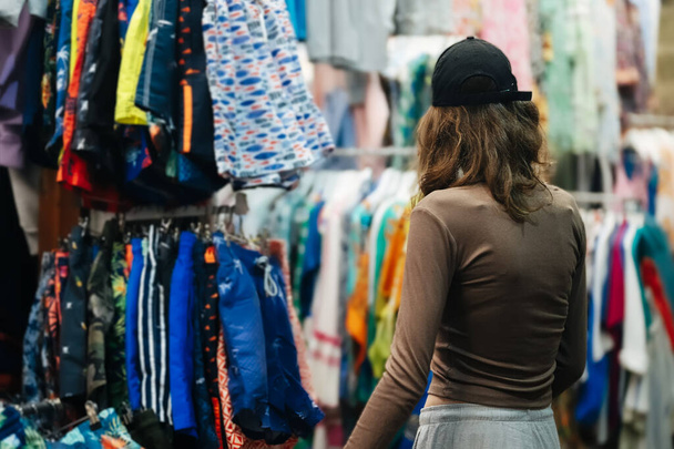 Adolescente chica elegir una ropa en el bazar de la noche. - Foto, imagen