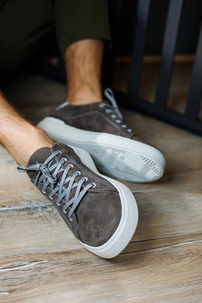 Мужские ноги в серых обычных кроссовках. Комфортная мужская летняя обувь. - Фото, изображение