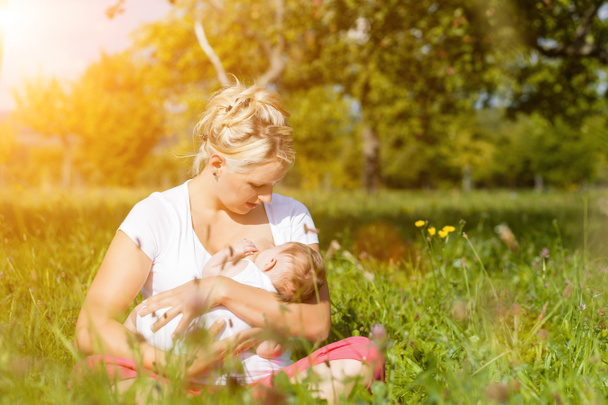 Äiti imettävät vauva niityllä
 - Valokuva, kuva