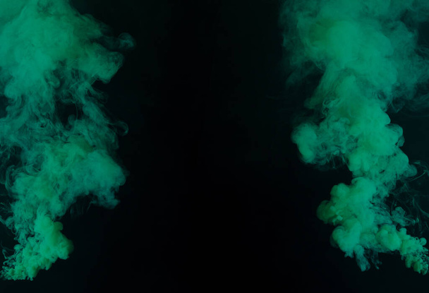 Zelené husté načechrané obláčky bílého kouře a mlhy na černém pozadí, Abstraktní kouřové mraky, rozostřený pohyb. Kouření údery ze stroje suchý led létat třepetání ve vzduchu, efekt textury - Fotografie, Obrázek