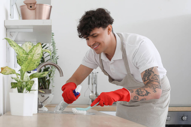 Mannelijke conciërge schoonmaken spoelbak in keuken - Foto, afbeelding