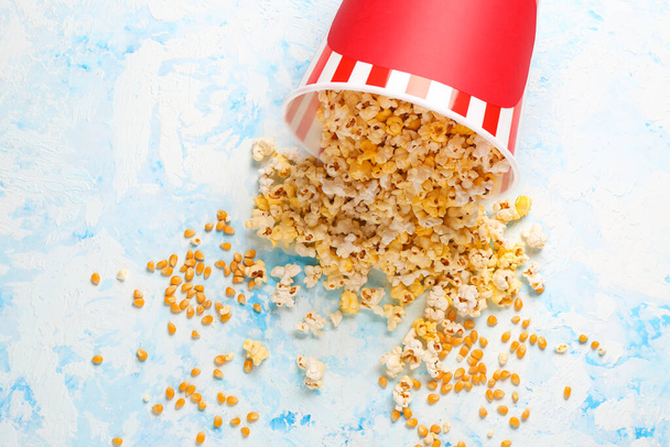 Bucket with tasty popcorn on light blue background - Photo, Image
