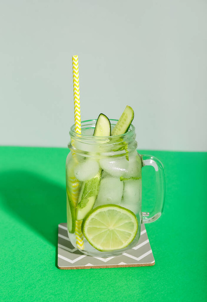 Cóctel Mojito con pepino, lima y hielo en frasco de vidrio sobre fondo verde - Foto, Imagen