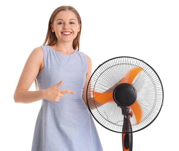 Mujer joven señalando ventilador eléctrico sobre fondo blanco - Foto, Imagen
