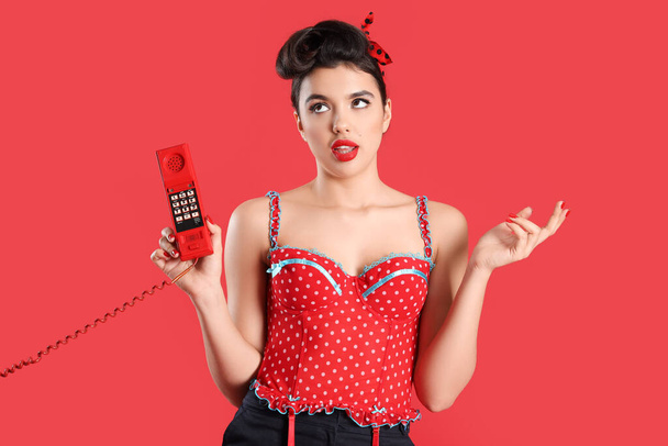 Kırmızı arka planda telefon ahizesi olan genç bir poster kadını. - Fotoğraf, Görsel