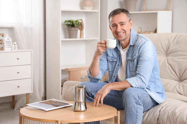 Homme mûr avec tasse et machine à café geyser sur la table à la maison - Photo, image