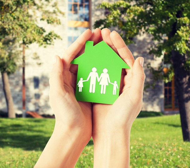 hands holding green house with family - Foto, immagini