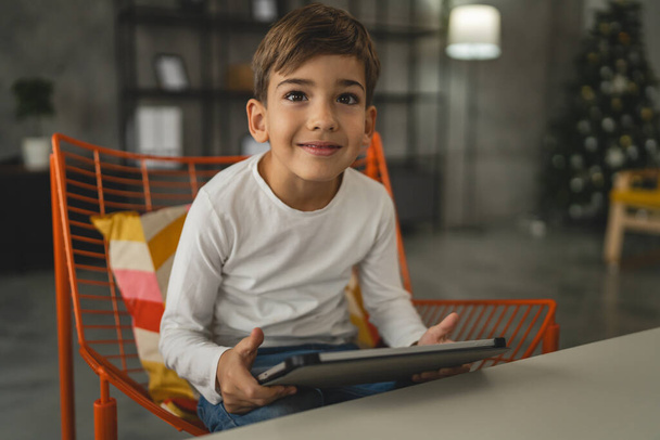 Uno scolaro caucasico ragazzo sedersi a casa uso tablet digitale - Foto, immagini