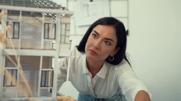 Молодой красивый кавказский архитектор переворачивает модель дома, чтобы осмотреть строительство дома и проверить место ошибки, чтобы решить проблему на столе для встреч в современном офисе. Крупный план. Непорочный. - Кадры, видео