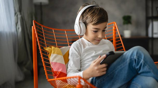 Um menino caucasiano estudante sentar-se em casa uso tablet digital - Foto, Imagem