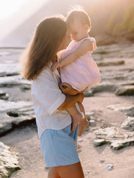Anne ve küçük kızı sahilde. Annenin çocuğuna olan sevgisi. - Fotoğraf, Görsel