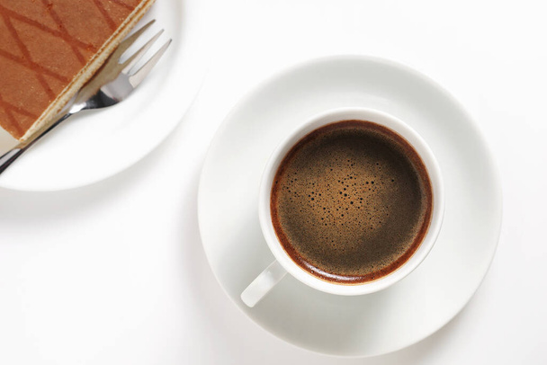 Šálek kávy a houba dort třešeň a smetanový koktejl na bílém pozadí, horní pohled - Fotografie, Obrázek