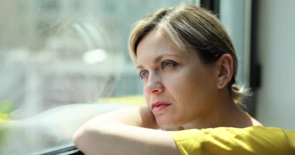 Szomorú, frusztrált fiatal nő gondolkodik és néz ki az ablakon. A személyes gondok és válások nehéz élethelyzeten mennek keresztül. - Felvétel, videó
