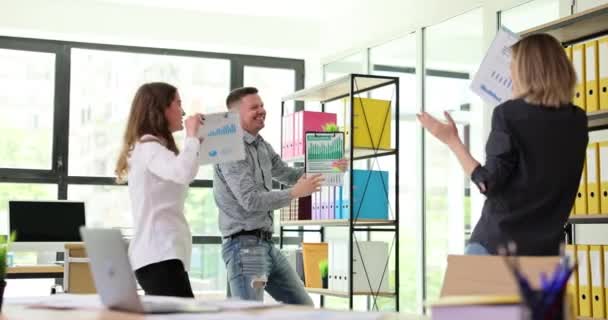 Vreugdevolle medewerkers dansen in een modern kantoor en vieren het algehele bedrijfssucces. Emotionele gelukkige collega 's medewerkers hebben plezier en ontspannen samen op de werkplek - Video