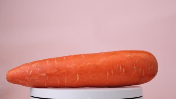 Porkkana pyörii vaaleanpunaisella taustalla. - Materiaali, video