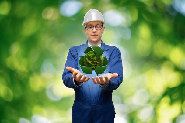 Engineer holding a green planet Earth with recycling symbol. - Fotó, kép