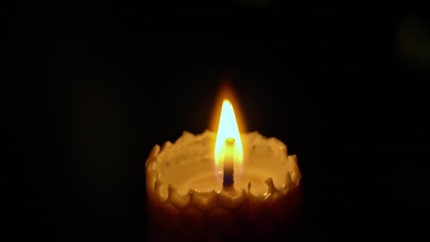 Wax candle burns on black background. Candle lights up yellow lights. Large fire of wax candle burns yellow. There is no light in house, warmth is from a candle. Poverty, war, minute of silence. - Footage, Video