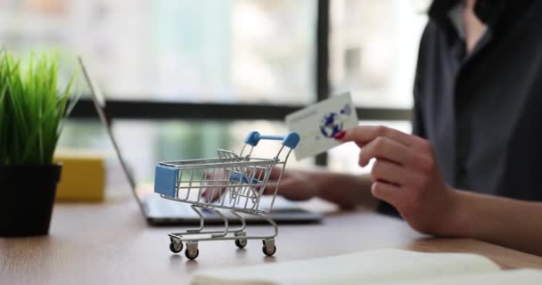 Bilgisayarı kredi kartı ve alışveriş arabasıyla online alışveriş yapmak için kullanan biri. E-ticaret internet bankacılığı ve para harcama kavramı - Video, Çekim