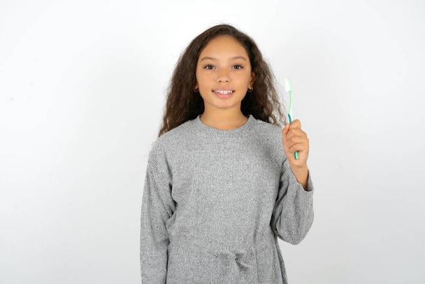 adolescente che indossa un maglione grigio con uno spazzolino da denti e sorridente. Concetto di assistenza sanitaria dentale. - Foto, immagini