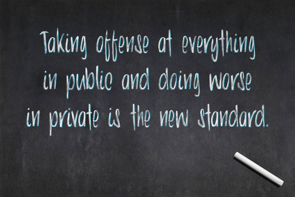 Blackboard with a quote saying "Taking offense at everything in public and doing worse in private is the new standard.", drawn in the middle. - Photo, Image