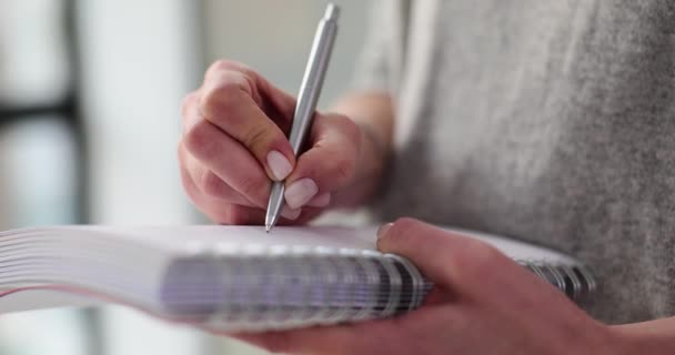 Onherkenbare vrouw schrijft orders of to-do lijst op in notitieblok. Vrouw neemt notities en schrijft informatie in notitieboekje - Video