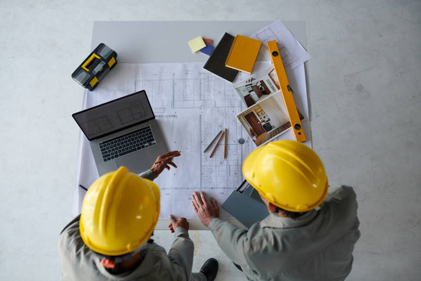 Инженеры-строители, работающие над проектом для клиента, проверка чертежей и визуализаций, вид сверху - Фото, изображение