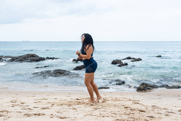 Portret van een mooie fitnessvrouw die zich uitstrekt over het strand zand. Gezonde levensstijl. - Foto, afbeelding
