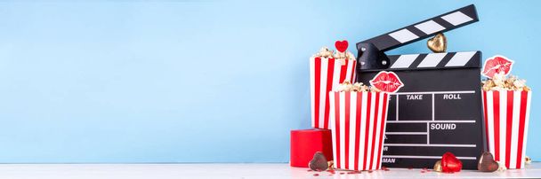 Romantikus dátum február 14-én Valentin napon. Szerelem film maraton, randi a moziban. Clapperboard, popcorn vödör, szív dekoráció és csokoládé piros háttér lapos másolási hely - Fotó, kép